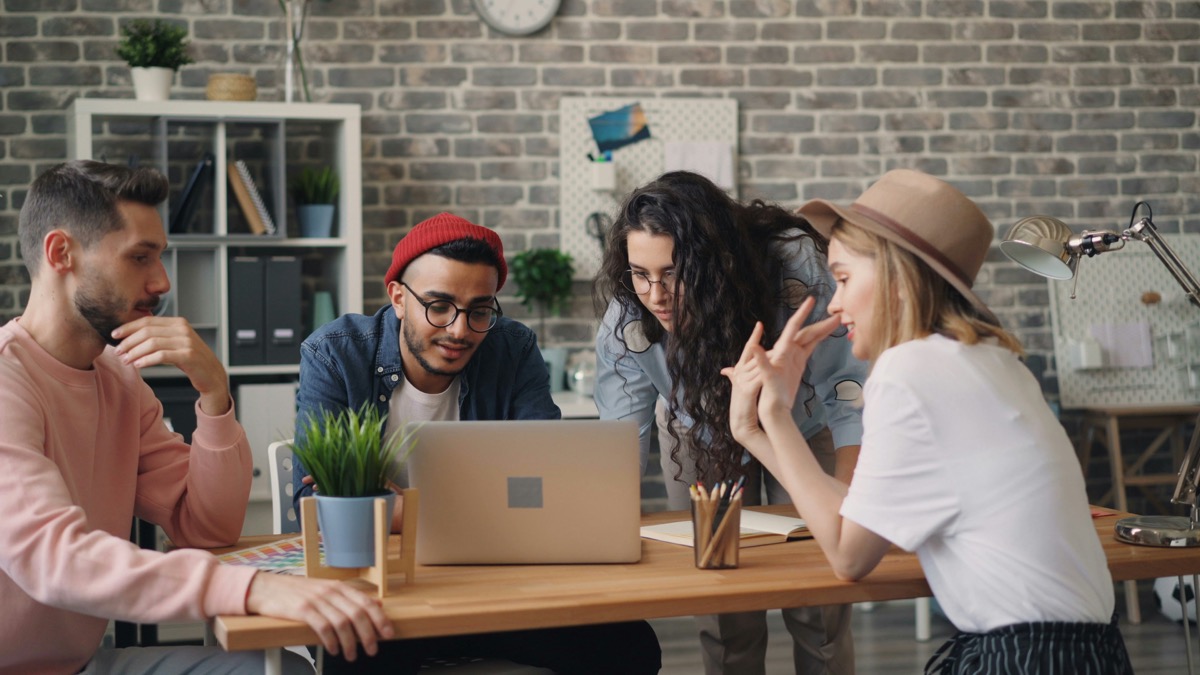 Equipo conversando y señalando un laptop mientras revisan un proyecto